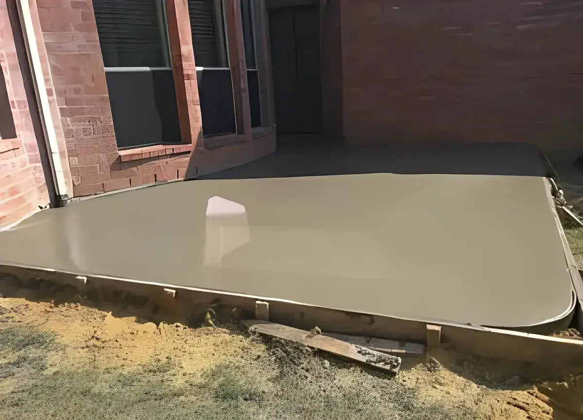freshly poured smooth concrete patio slab against a brick wall in Royal Palm Beach