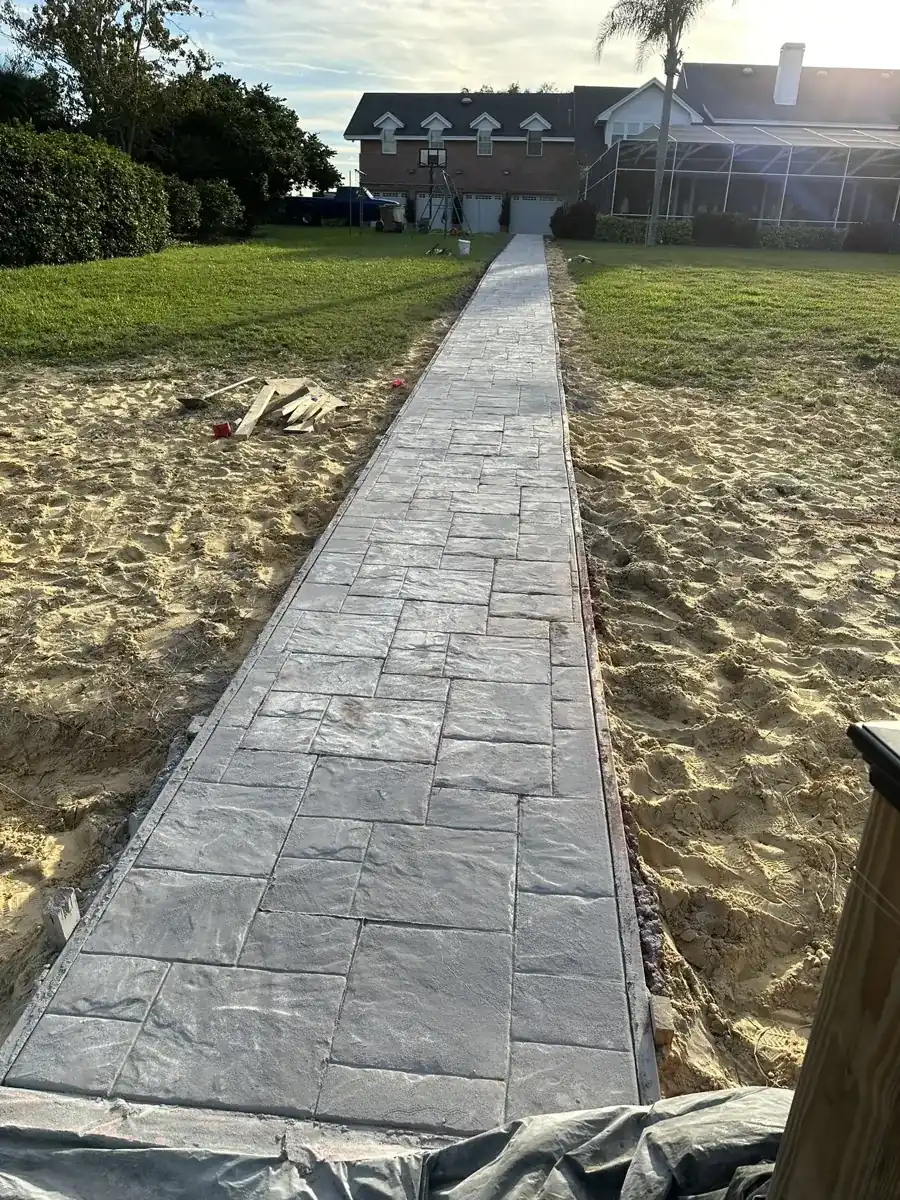 long stamped concrete walkway across a sandy yard to a house in Royal Palm Beach