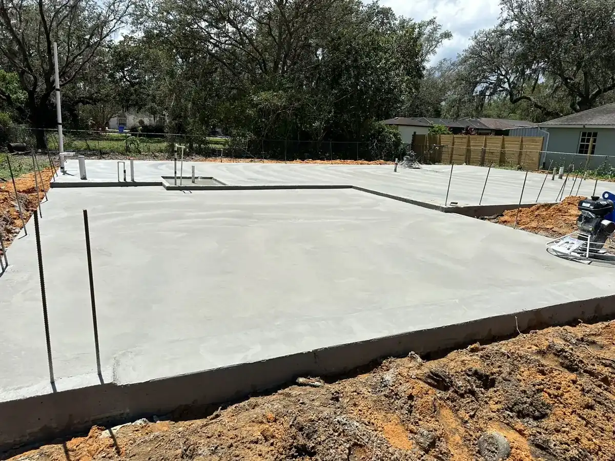 new concrete slab foundation with plumbing stubs on a cleared lot in Royal Palm Beach